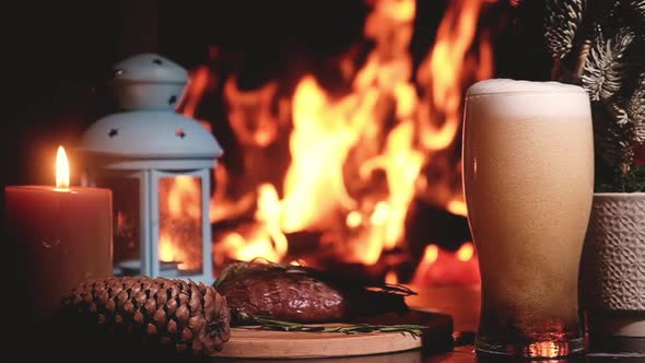 Cold beer poured from bottle glass on background of burning fireplace