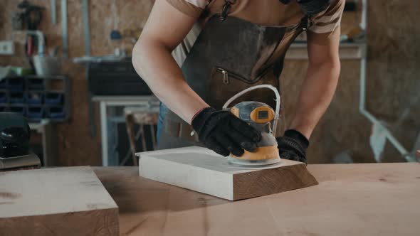 The Carpenter Works with the Electric Polisher on the Wood. Top View Man Craftman with Grinder