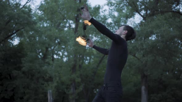 Young Man in Black Clothes Performing a Show with Flame Standing on Riverbank