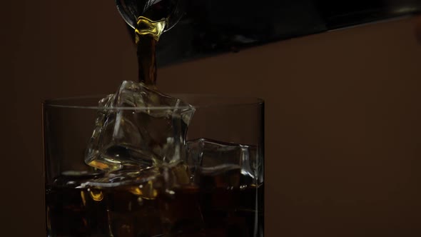 Pouring Whiskey, Cognac Into Glass. Dark Background. Pour of Alcohol Drink