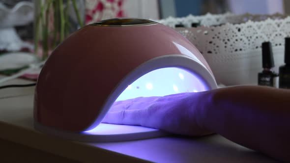 A Woman Dries Her Nails In An Ultraviolet Lamp. She Gives Herself A Manicure.