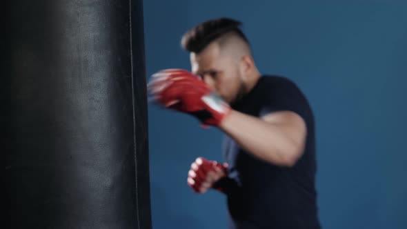 Muscular Handsome Fighter Giving a Forceful Forward Kick During a Practise Round with a Boxing Bag