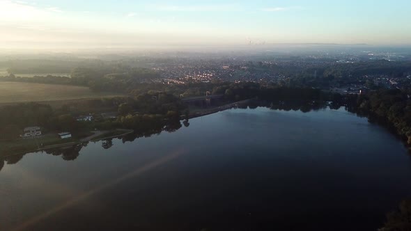 Slow forward moving aerial over reservoir,lake on sunrise misty morning towards bridge.