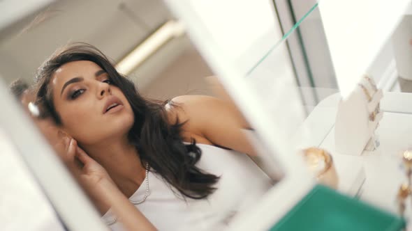 Woman Trying on Earrings in the Mirror