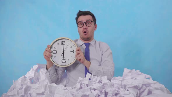 Confused Man Office Worker with a Watch Leans Out of a Large Heaps of Crumpled Paper