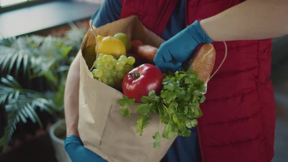 Close Up Cardboard Box with Food in Hands in Medical Gloves