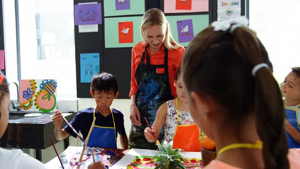 Teacher assisting schoolkids in drawing class