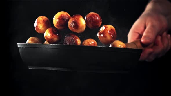 A Man's Hand Tosses Fried Potatoes in a Frying Pan