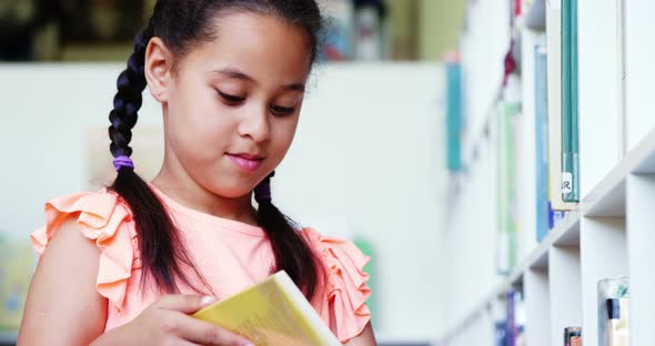 Schoolgirl reading book in library at school