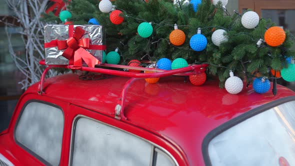 Red Retro Car with a Christmas Tree Fir Tied to the Roof