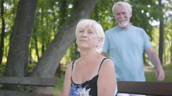 Portrait of Adorable Mature Woman Sitting on the Bench in the Park