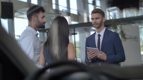 Attractive Young Couple Choosing Car at Dealership