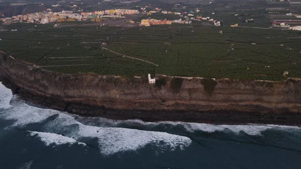 Cliffs with banana plantation fields and solidified lava in sea after volcano eruption at La Palma.