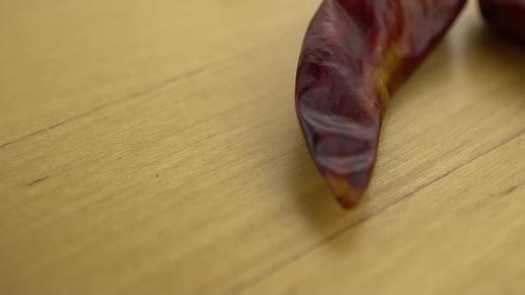 One Piece Chili Peppers Falling on a Wooden Surface. Macro Shot of Red Pepper. Slow Motion.