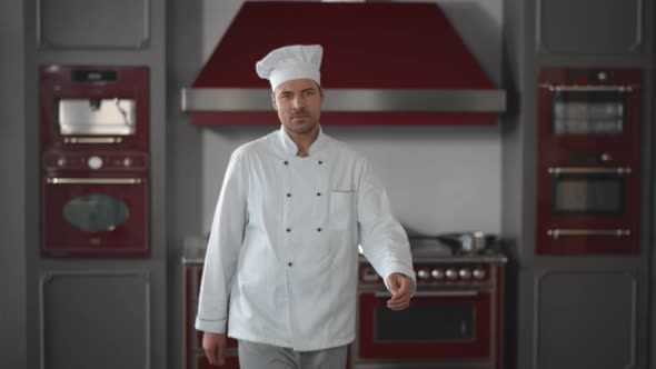 Portrait of Smiling Chef in Modern Industrial Red Kitchen Posing at Camera with Crossed Hands