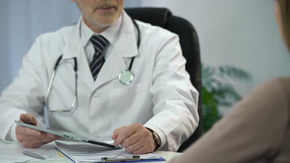 Physician Talking to Patient and Checking Medical Records on His Tablet PC