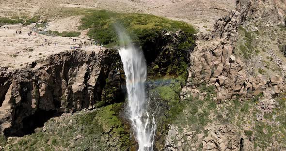 Aerial orbit of the inverted waterfall with a constant rainbow around it in Maule, Chile on a sunny