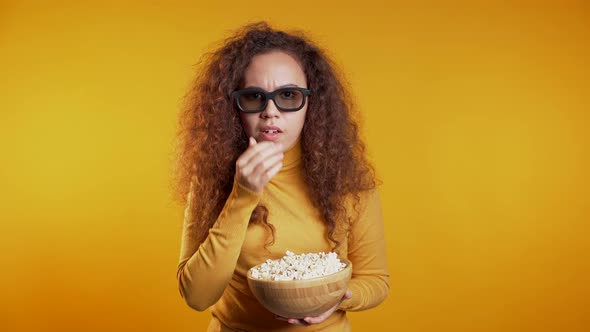 Young Woman in 3d Glasses Watching Movie and Eating Popcorn on Yellow 