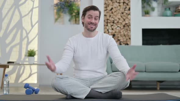 Young Man Talking on Video Call on Yoga Mat at Home