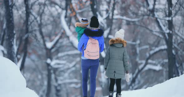 Happy Mother Walks with Children in the Winter Forest