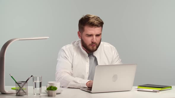 Young Business Man Thinking Intently and Typing on Laptop Keyboard