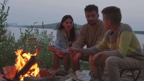 Family Roasting Sausages by Bonfire