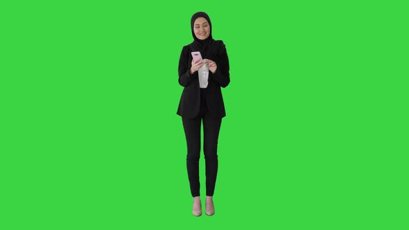 Young Muslim Woman Wearing Hijab Headscarf Walking Using Smartphone on a Green Screen, Chroma Key