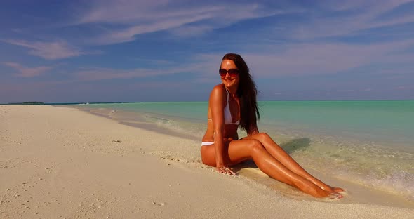 Beautiful happy lady on photoshoot having fun at the beach on summer white sand and blue 4K backgrou