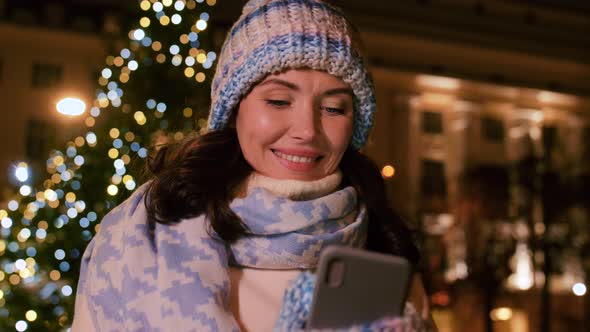 Happy Woman with Smartphone in Christmas City