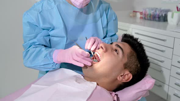 Female Dentist Examining a Patient with Tools in Dental Clinic