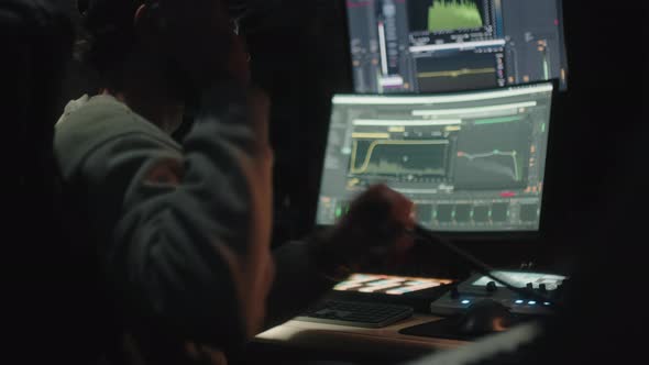 Sound Engineer Seen Seated From Behind Uses the Computer to Mix Audio Music