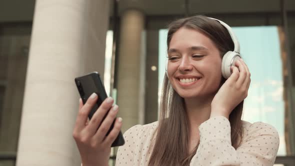 Woman with Smartphone and Headphones Smiling