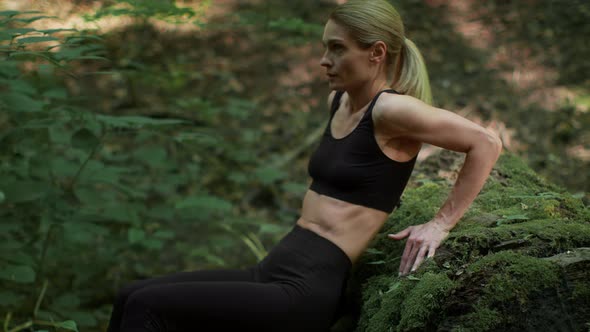 Middle Aged Woman Exercising at Woodland Practicing Reverse Pushups Leaning at Mossy Stone Tracking