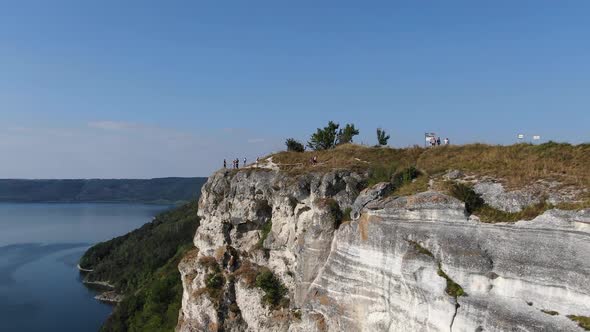 Aerial VIew of People Looking Over a Cliff on a River on a Bright Sunny Day
