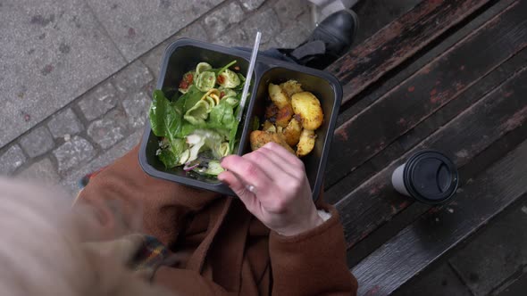 woman eating a salad on city bench