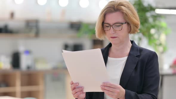Portrait of Old Businesswoman Reading Papers in Office