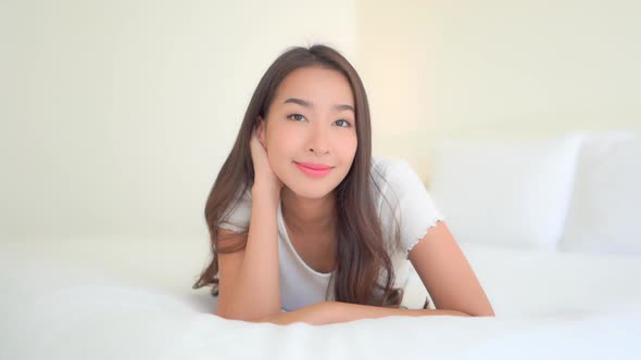 Asian woman relax on bed in bedroom interior