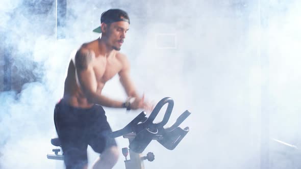 Shirtless Athletic Man Training on Cycling Machine in Gym