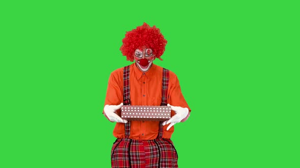 A Happy Male Clown Holding a Present and Walking on a Green Screen Chroma Key