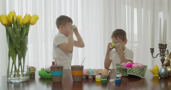 Two Little Brothers Jump Like Bunnies with Colored Eggs in Their Eyes