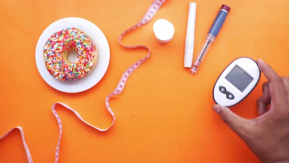 Diabetic Measurement Tools Insulin and Donuts on Orange Background