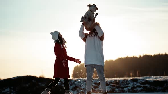 Happy Young Couple Walking on Winter Frozen Lake with Their Doggy