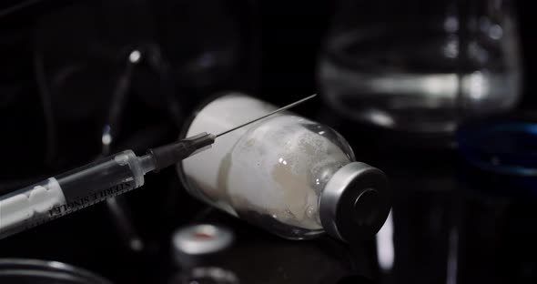 Laboratory Equipement: Syringe and Medicine, Test Tubes and Flasks Rotating on Black Background