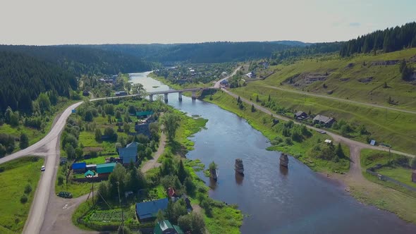 Top View of Bridge Over River in Green Valley with Small Town