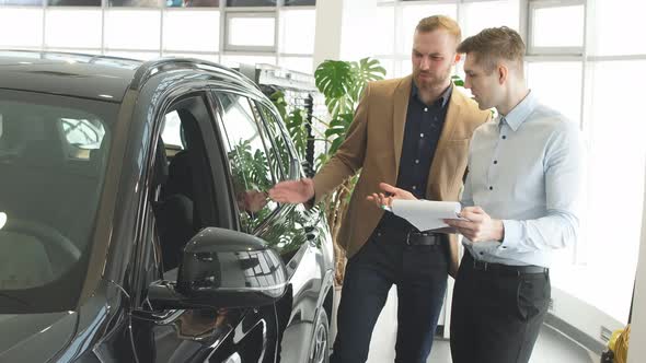 Handsome Young Cars Salesman Help Customer with Choose.