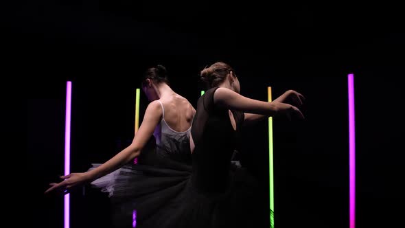 Camera Circular Motion Around Young Ballerinas Dancing on a Black Studio Background with Bright Neon