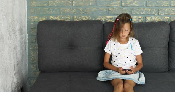 Child using cellphone on the sofa in modern and bright apartment