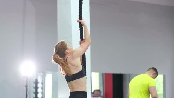 Strong sporty woman trains on a rope in the gym