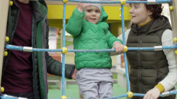 Boy Climbing at Playground and Parents Guarding Him alt