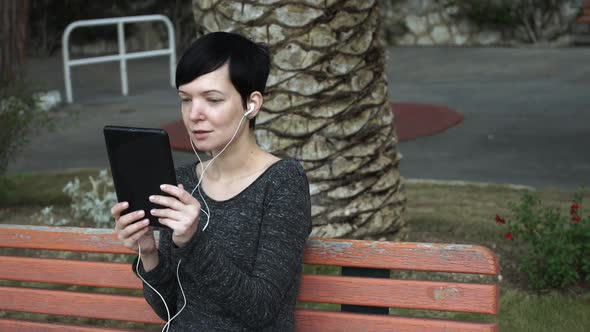 Woman Using App on Touch Screen Tablet for Video Call at Playground